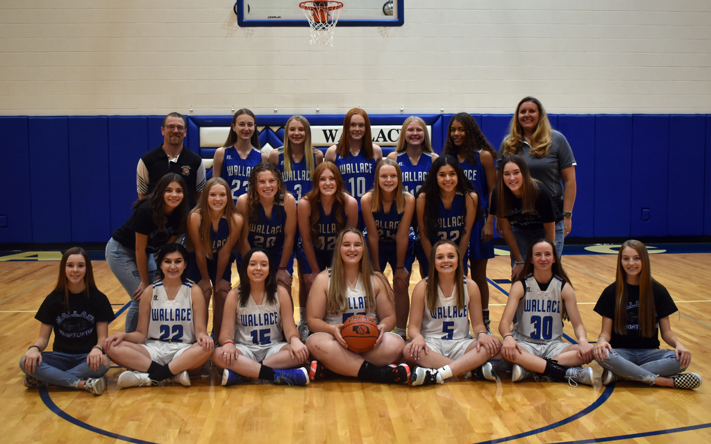 Girls basketball team pose on basketball court